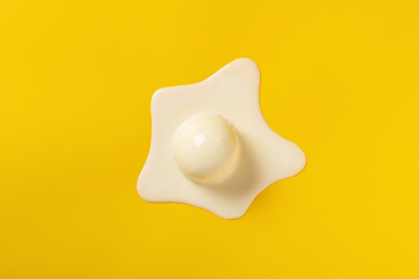 俯视图香草口味冰淇淋球在熔化过程中的黄色背景图片下载