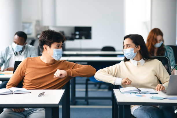 各式各样的学生戴着口罩打招呼、碰撞手肘素材图片