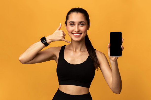 快乐的运动型女子展示带有空白屏幕的手机。图片下载