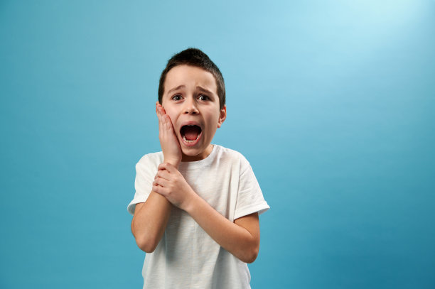 在蓝色背景下，一个男孩捂着自己的脸颊，痛苦地尖叫着图片下载