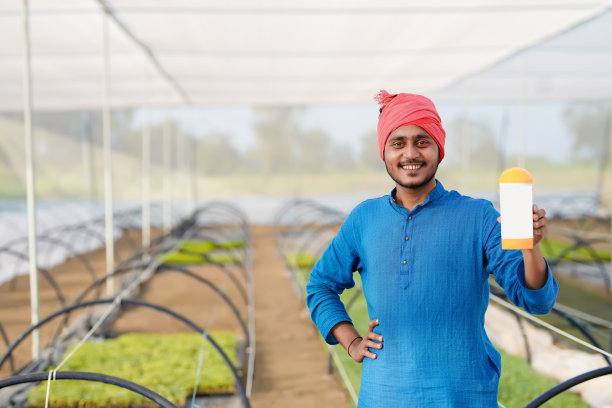 年轻的印度农民在温室展示肥料瓶图片下载