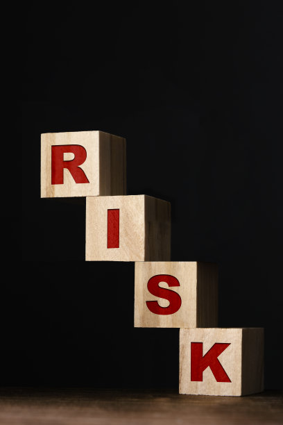 “风险”写在玩具积木上勉强站立，黑色背景图片下载