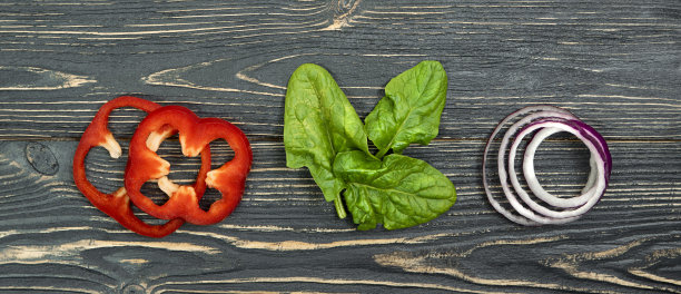 切成薄片的红辣椒，菠菜叶，洋葱在深色的木质背景上。图片下载