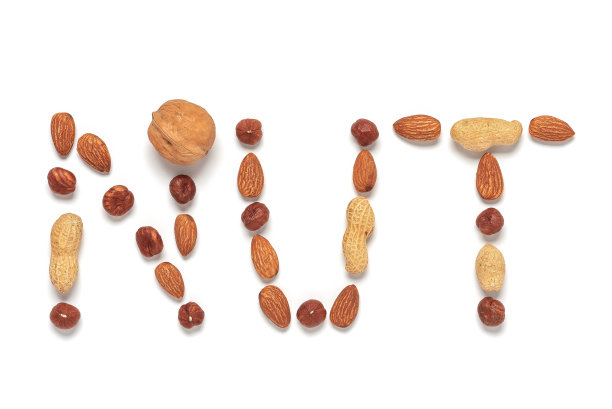 收集各种坚果。“坚果”这个词是由不同的坚果分离在白色的背景。创造性的布局。俯视图，平放。图片下载