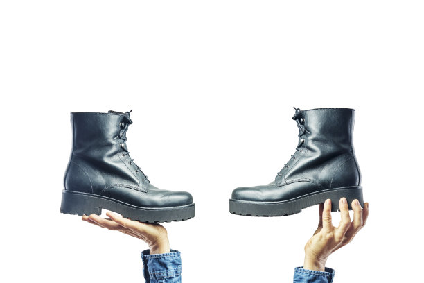 手握黑人妇女的靴子在白色的背景。鞋子的选择,购物图片下载