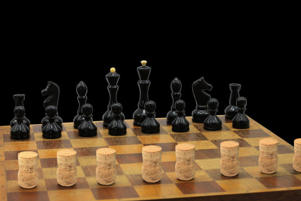 抽象照片与棋子和葡萄酒软木在棋盘上的黑色背景图片下载