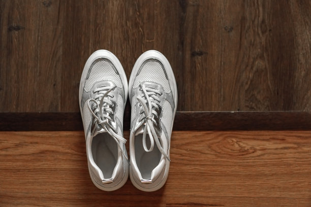 木质地板上的白色运动鞋有两种颜色。前视图。图片下载