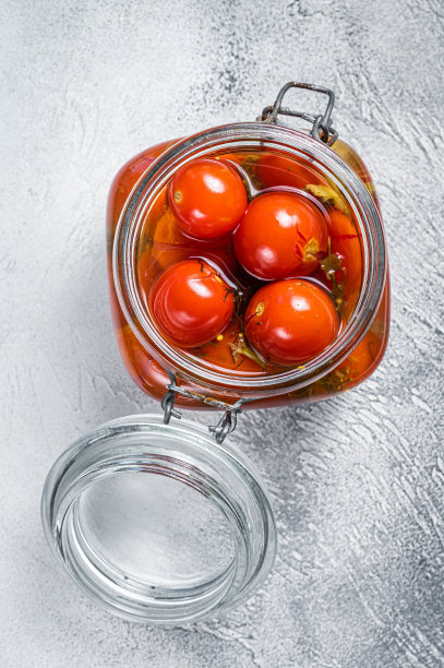 在玻璃罐里腌制的樱桃番茄。白色背景。俯视图图片下载