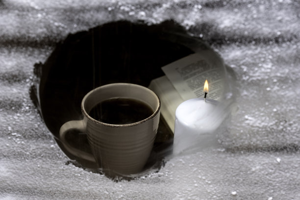 书，一杯咖啡，蜡烛在白雪覆盖的窗户后面图片下载