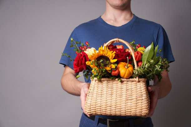 一个戴着手套的男人的手，灰色背景上有一篮子花图片下载
