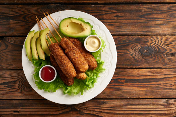 美味的玉米热狗配酱汁和沙拉，盛在白色的盘子里图片下载