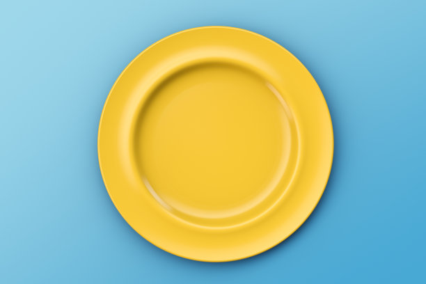 蓝色桌子上的黄色空盘子。就像天上的太阳。俯视图图片下载