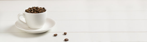 Banner咖啡豆放在一个白色的咖啡杯里，白色的背景上有几颗咖啡豆。图片下载