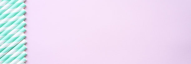 一堆纸条纹白色和绿色的饮料吸管在粉红色的背景。空间的文本。横幅图片下载