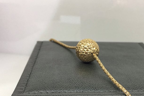 棕色首饰盒上挂着一条粗粗的金链子和一个球坠。图片下载