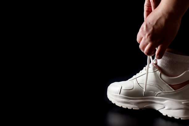 系鞋带在白色运动鞋上，孤立在黑色背景与拷贝空间。图片下载