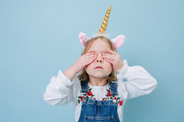 有趣好玩的小女孩在独角兽头带在蓝色的背景图片下载