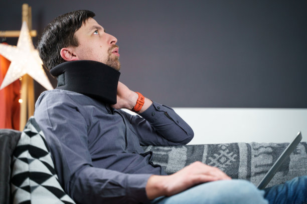 商人超时工作时疼痛时按摩脖子，用颈圈来缓解肌肉紧张。一个有健康问题的人因过度工作而颈部受伤或麻木图片下载