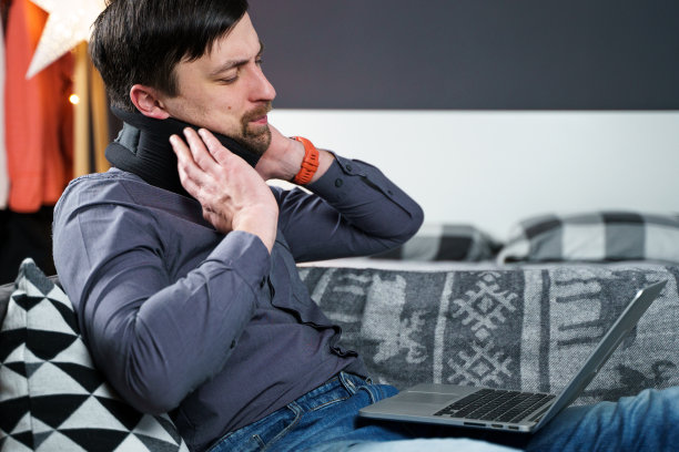 商人超时工作时疼痛时按摩脖子，用颈圈来缓解肌肉紧张。一个有健康问题的人因过度工作而颈部受伤或麻木图片下载