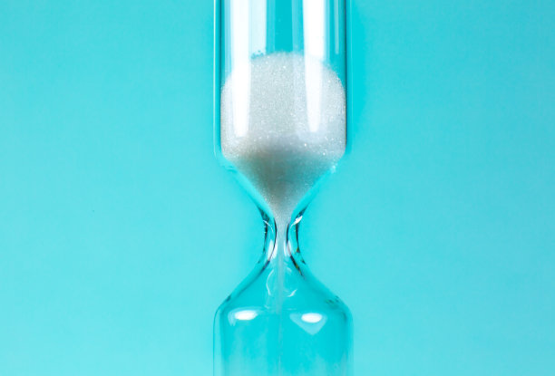 沙钟在绿松石背景上。沙漏作为时间流逝的概念。近距离的照片。图片下载