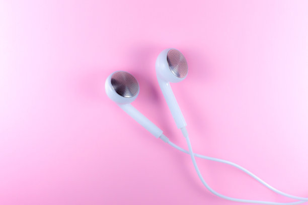 白色耳机躺在粉红色的背景上。现代音乐的概念。音频技术。近距离的照片。图片下载