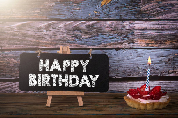 生日快乐。水果蛋糕和一周年纪念蜡烛在木背景图片下载