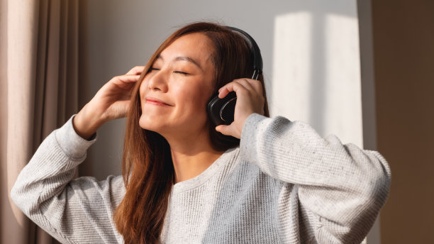 一位年轻美丽的亚洲女子喜欢在家里用耳机听音乐图片下载