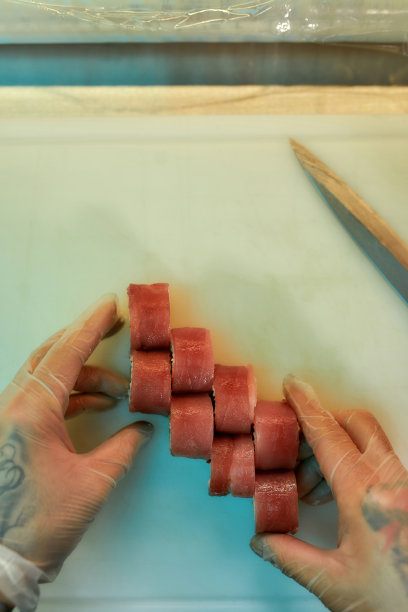 俯视图厨师安排金枪鱼寿司切片，同时准备在商业厨房的板上卷图片下载