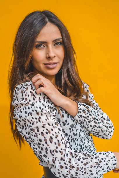 时尚拍摄，一个美丽的白人黑发在白色的裙子，与黄色的背景图片下载