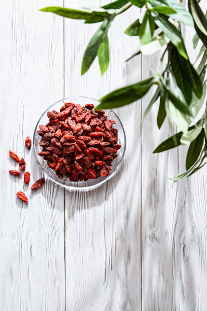 白色木桌上的玻璃盘子里放着干枸杞。有机，天然，中国枸杞组成。超级食物。健康的生活方式的概念。图片下载