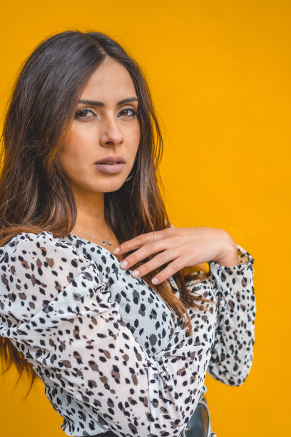 生活方式，一个美丽的白人深褐色在白色的裙子与黑点，与一个黄色的背景背后图片下载