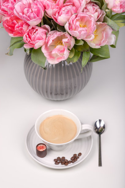 一顶咖啡加糖和咖啡豆的帽子，在插着花的花瓶旁边图片下载