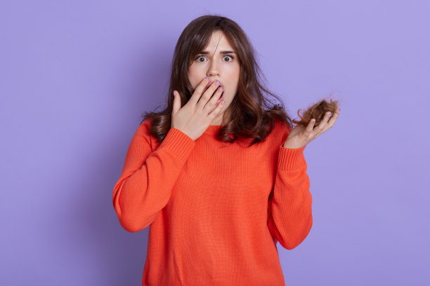 美丽的欧洲女人，拿着散乱的头发，看起来很害怕和惊讶，惊讶地盖住张开的嘴，难以置信的脸，看着相机的大眼睛，有问题的头发，头发厕所。图片下载