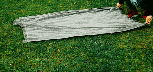 一位中年男子在公园里铺开毯子图片下载