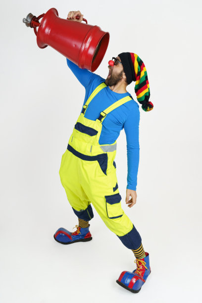 小丑消防员手里拿着一个火桶在他的面前——他看着它。图片下载