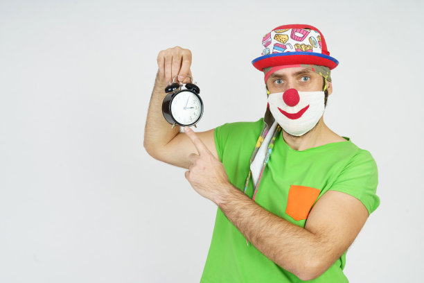 小丑手里拿着一个闹钟。孤立在白色图片下载