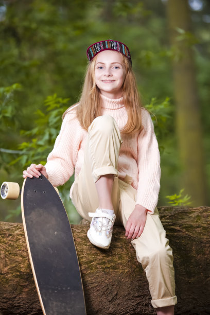 青少年生活方式概念：快乐的白人少女在楼梯上摆姿势，手持长板。竖版构图图片下载