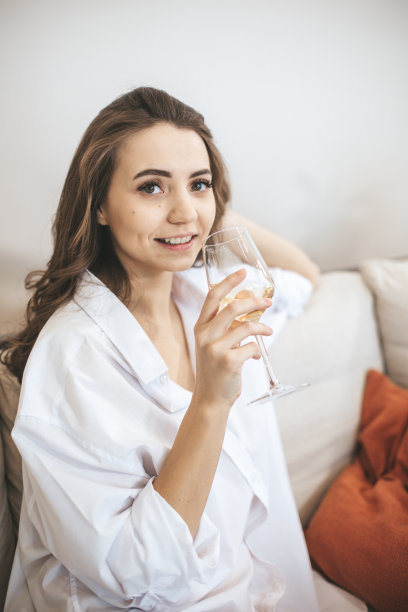 年轻女子在家里喝着酒。图片下载
