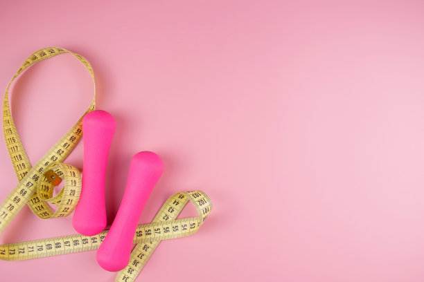 粉色背景上的哑铃和卷尺，俯视图。37、运动的理念，健身健康的生活方式。图片下载