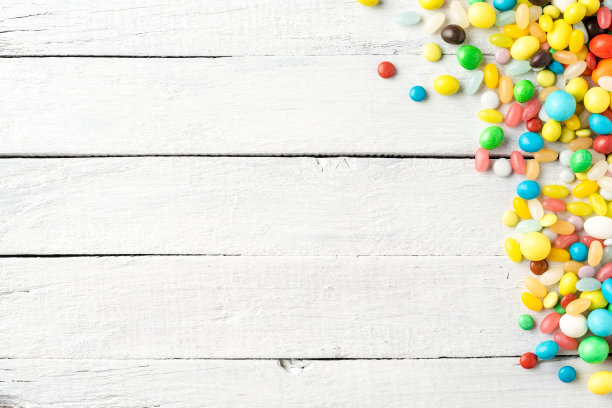 头顶上不同的糖果在白色木制背景。不健康食品的概念图片下载