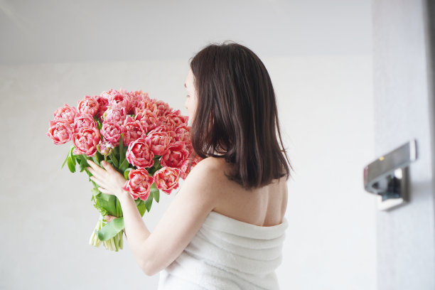 身着晨袍，手持一束牡丹郁金香的女孩。一个浪漫早晨的气氛。图片下载