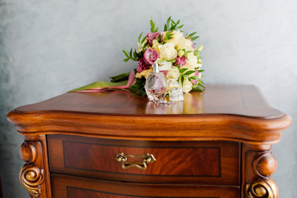 床头柜上放着带香水的结婚戒指和结婚花束。婚礼象征属性。图片下载