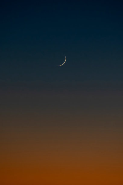 一个轮廓的月亮与一个蓝色和橙色阴影在背景图片下载