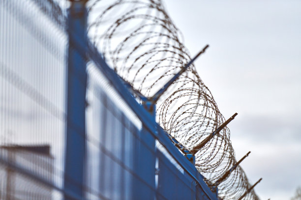 禁区蓝色围栏上的带刺铁丝网图片下载