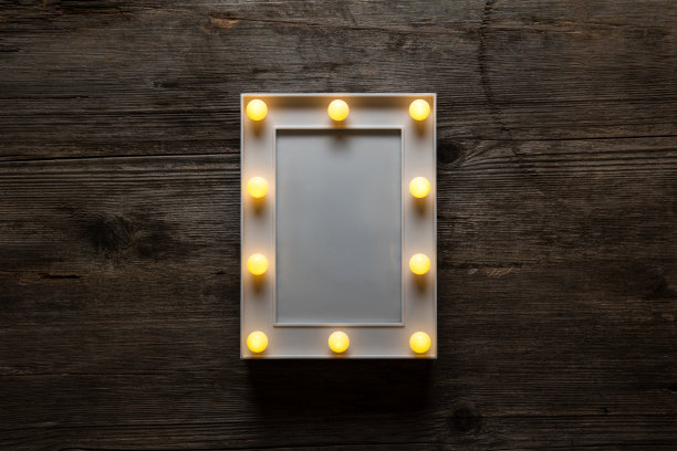 发光的白色框架与灯泡在一个古老的木制背景。空白的海报或明信片。图片下载