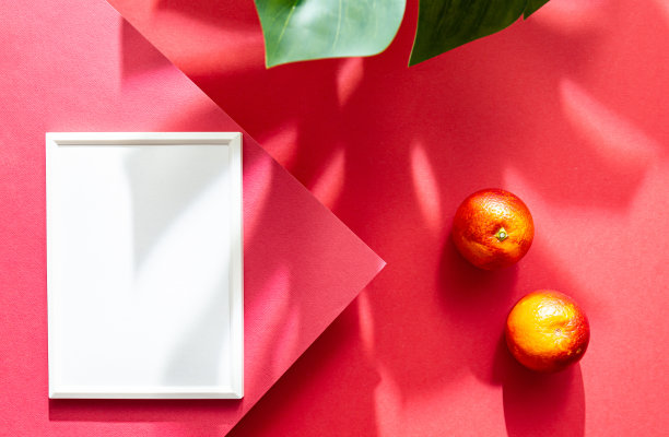 模拟海报白色相框俯视图。明亮的夏季静物场景与橙子水果和怪兽棕榈叶。平躺在红色背景上图片下载