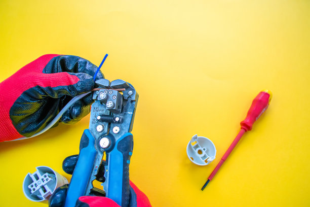 电工从电线上剥去绝缘。特写手和钳子。有选择性的重点图片下载