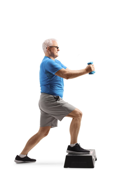 一个成熟的男人用哑铃在一个踏步有氧平台上锻炼的全长侧面照片图片下载