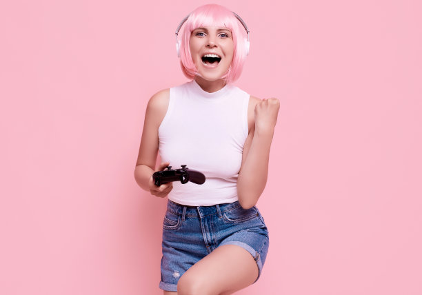 快乐性感的玩家女孩与粉红色的头发玩视频游戏使用操纵杆图片下载