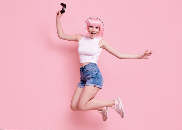 快乐性感的玩家女孩与粉红色的头发玩视频游戏使用操纵杆图片下载